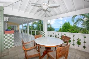 a porch with a table and chairs and a ceiling fan at Casa Afortunada - 2 bedrooms in Sandy Bay