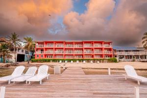 a red building with white chairs on a boardwalk at Mayan Princess Hotel in San Pedro