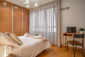 a bedroom with a bed and a desk and a television at Apartamento Massastur in Gijón +24 photos
