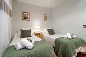 two beds in a white room with green sheets and pillows at Apartamento Massastur in Gijón