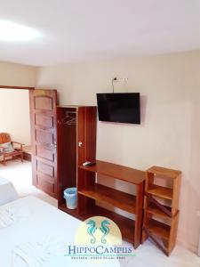 a bedroom with a desk and a tv on the wall at Pousada Hippocampus in Porto De Galinhas