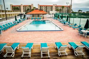 a pool at a resort with lounge chairs and a building at Ocean Landings Resort & Racquet Club in Cocoa Beach