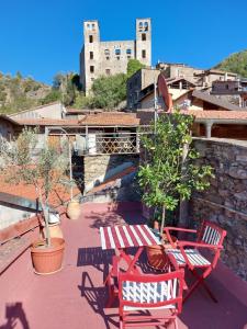 un patio con sedie rosse, un tavolo e un castello di B&B Le Gemme a Dolceacqua