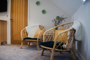 two wicker chairs sitting in a room with a door at Sam's Place Apartment in Uppingham, Rutland in Uppingham