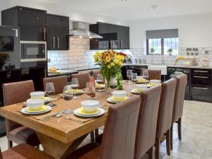 - une cuisine avec une table en bois, des chaises et des fleurs dans l'établissement Coombe Wood Coach House, à Hawkinge