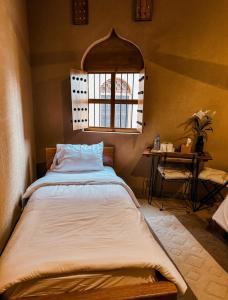 a bed in a room with a window and a table at Alaqur View Inn نزل واجهة العقر in Nizwa