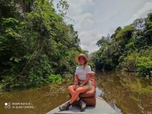 una mujer sentada en un barco en un río en Jacamar Lodge Expeditions, en Iquitos
