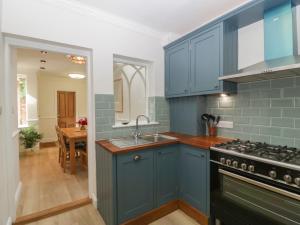a blue kitchen with a sink and a stove at Thyme Cottage in Great Malvern