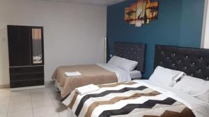 1 dormitorio con 2 camas y pared azul en HOSPEDAJE BLESS en Trujillo