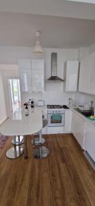 a kitchen with white cabinets and a white table at Primrose Hill - Charming, Cosy, 2 Double Bedrooms Apartment in London