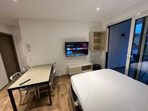 een kamer met een bed, een bureau en een televisie bij Riva Lake Lodge in Riva del Garda