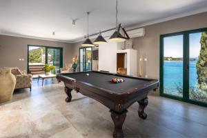 a pool table in a room with a view of the water at Villa Mare Vista in Žman +18 photos