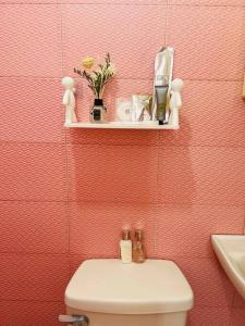 a bathroom with a toilet and a pink wall at Cara Transient house in San Pablo