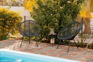 - deux chaises noires installées à côté de la piscine dans l'établissement Studio B, à Port-Louis