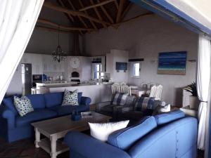 una sala de estar con sofás azules y una mesa. en Bokmakierie Villa en St Helena Bay