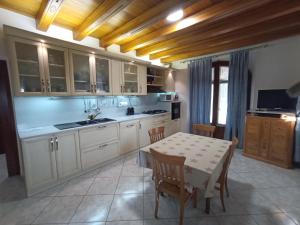 una cocina con armarios blancos y una mesa con sillas. en Villamoreno, en Merlara