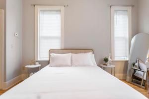 een groot wit bed in een kamer met 2 ramen bij The Matisse at Wooster Square Yale with Parking in New Haven