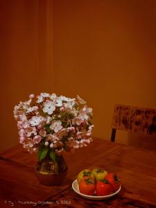 a vase with flowers and apples on a table at THEN'S HOUSE Y TÝ in Phan Kơng Su