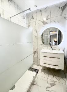 Baño blanco con lavabo y espejo en Le Golf Sauna - Cosy & SPA - 1 chambre - 2 pers, en Saint-Étienne