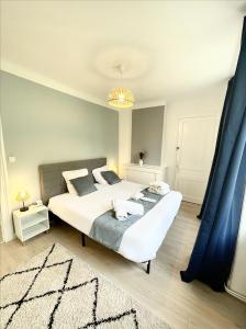 1 dormitorio con 1 cama blanca grande y cortinas azules en Le Golf Sauna - Cosy & SPA - 1 chambre - 2 pers, en Saint-Étienne