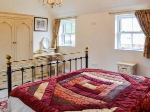 una camera con un letto con una trapunta sopra di The Parlour a Ferndown