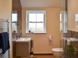 a bathroom with a sink and a toilet and a window at The Parlour in Ferndown
