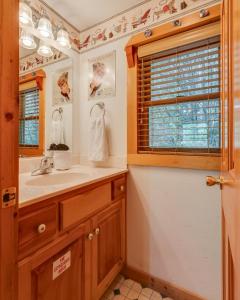 a bathroom with a sink and a mirror and a window at Hugs N Kisses Pool Table Hot Tub Pool Table Community Pool Close to Downtown Gatlinburg in Gatlinburg