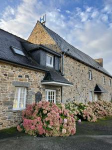 a stone house with flowers in front of it at Hôtel Les Voisins Beaucemaine in Ploufragan