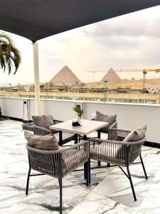a patio with a table and chairs with pyramids in the background at Peace Inn West Pyramids Cairo in Cairo