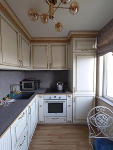 La cuisine est équipée de placards blancs et d'un four avec plaques de cuisson. dans l'établissement Provence apartment, à Šiauliai
