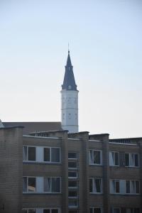 a tall white clock tower on top of a building at Provence apartment in Šiauliai