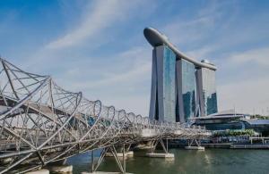 a large metal bridge over the water with buildings at 2Bedroom apartment near Orchard RD! in Singapore