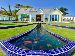 a house with a koi pond in front of a house at Pentire in Holbeton