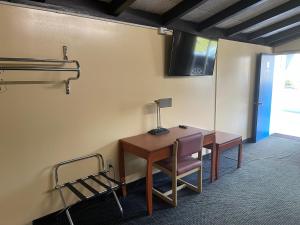 Budget Inn - Madison في Madison: غرفة بها مكتب وكرسي وطاولة
