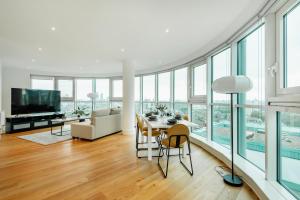 a living room with a table and chairs and glass windows at Vauxhall Skyline Apartment in London