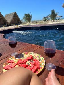 Playa Escondida Mayapo في Mayapo: طاولة مع طبق من الطعام وكأسين من النبيذ