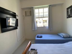 Habitación con 2 camas, TV y ventana. en STUDIO COMPLETO na praia de COPACABANA, perto Ipanema Gal Osório, com ar, wifi, netflix, até 3 pessoas, pauloangerami SF138, en Río de Janeiro