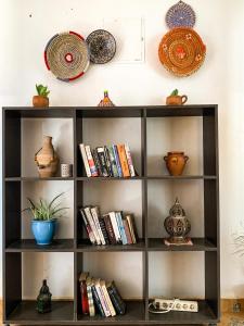 a book shelf with books and plates on a wall at Arima Surf House in Tamraght Ouzdar