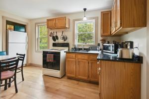 uma cozinha com armários de madeira e um frigorífico branco em Hillsborough Village Retreat Walk to River! 