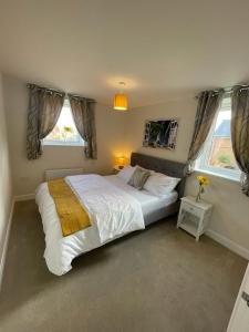 a bedroom with a large white bed and two windows at Spacious Apartment in Brooklands in Milton Keynes