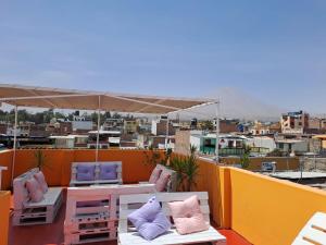 einen Balkon mit einem Tisch, Stühlen und einem Sonnenschirm in der Unterkunft Peru Swiss Hostel in Arequipa