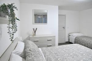een witte slaapkamer met 2 bedden en een spiegel bij THE BAC HOUSE - Maestrale in Fano