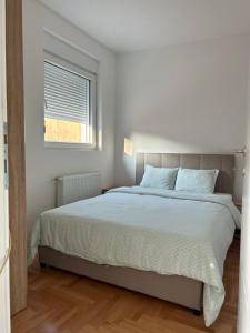 a white bedroom with a large bed with a window at House Inn 2 in Pirot