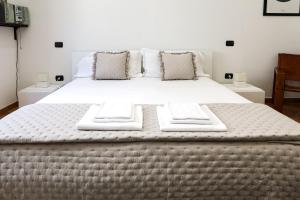 un grande letto con lenzuola e cuscini bianchi di GoodStay Central Suite -Terrace & Charme- a Lecce