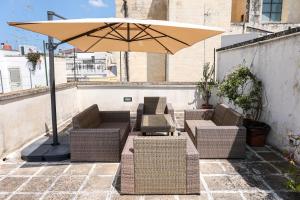 an umbrella sitting on a patio with wicker furniture at GoodStay Central Suite -Terrace & Charme- in Lecce