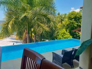 a view of a swimming pool with chairs and a palm tree at A Son de Mar - Playa Las Gatas acceso por mar in Zihuatanejo