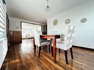 a dining room with a wooden table and white chairs at Downtown’s Sweet House in Puerto Natales