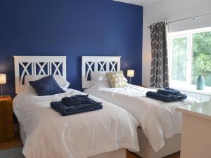 two beds in a bedroom with blue walls at Spring Cottage in Kentisbury