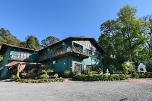 a large green building with a balcony at Pousada Três Pinheiros in Gramado