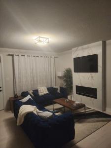 sala de estar con sofá azul y TV en Dorothy's Deluxe room, en Ottawa